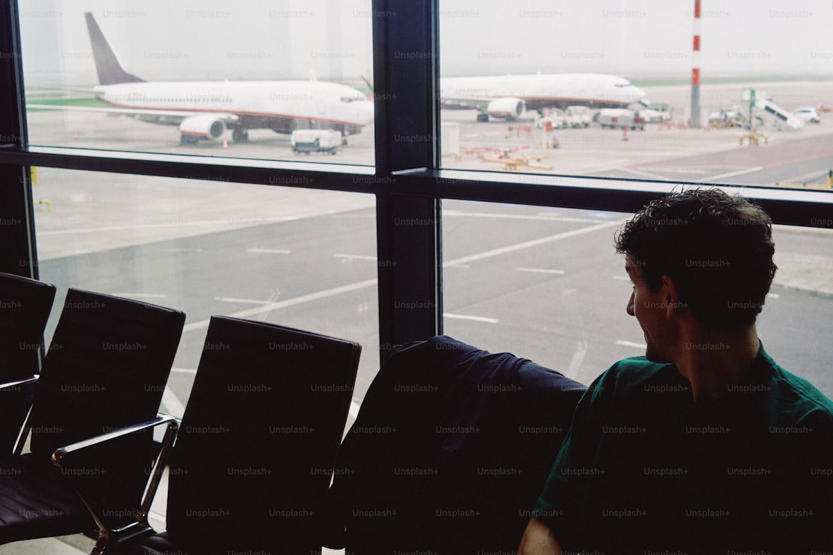 Viajante no aeroporto observando aviões pela janela